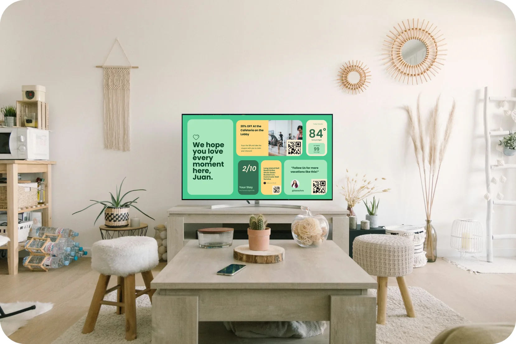 A living room where the TV shows a StayCast welcome screen greeting a guest by name, with weather, Wi-Fi and local offers.
